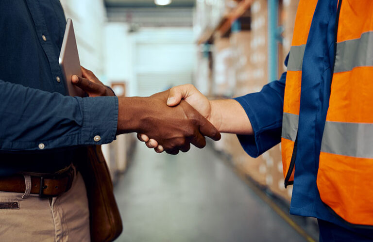 Two people shaking hands in a warehouse